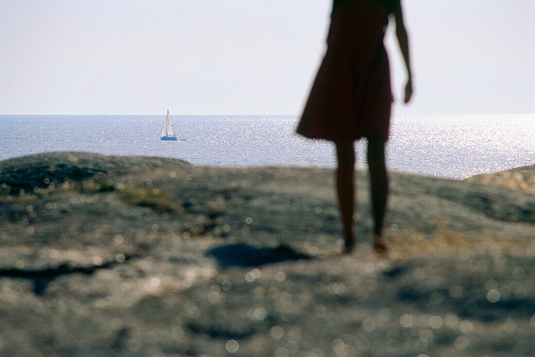 Frau steht auf Granitfelsen und blickt aufs Meer, Smögen, Bohuslan, Schweden