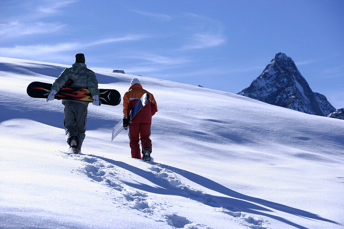 Two people with snowboards walking through snow, Hintertux Glacier, Zillertal, Tyrol, Austria