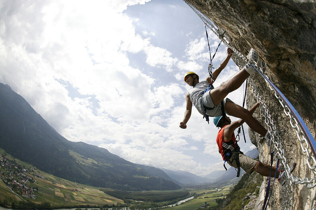 Two men climbing in a spiders web at Crazy Eddy, Haiming in the background, Tyrol, Austria
