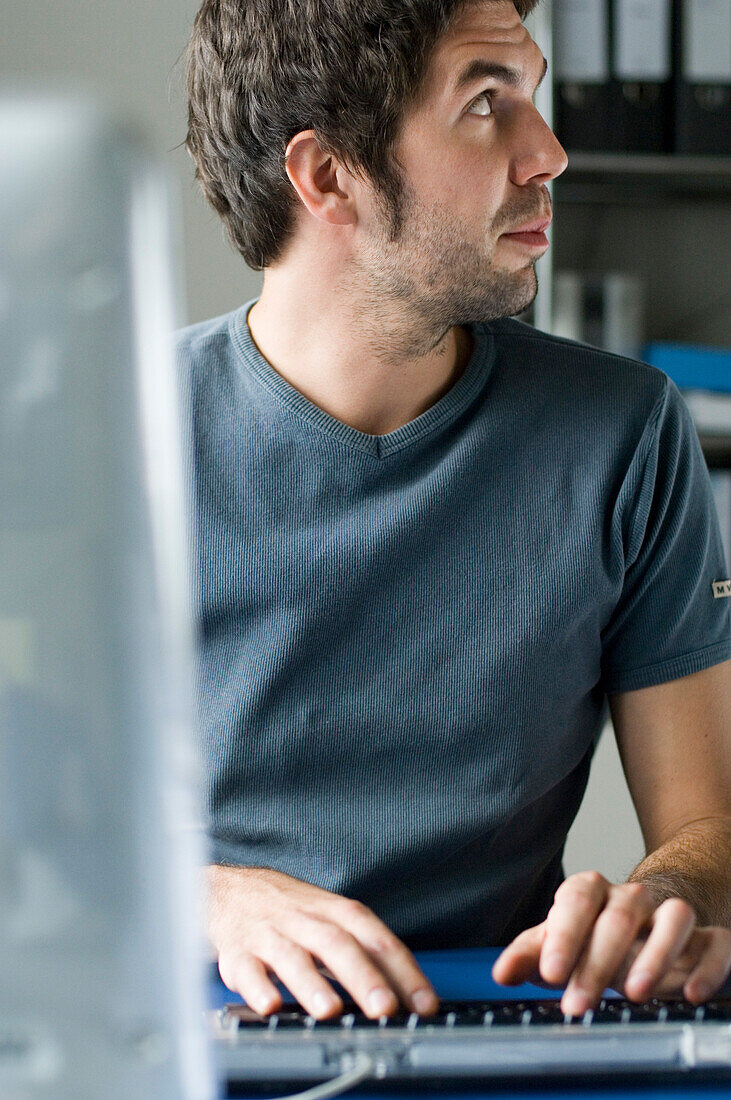 Young man using computer, looking sidewards