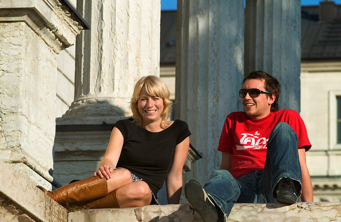 Couple sitting in front of Academy of Fine Arts, Munich, Bavaria, Germany