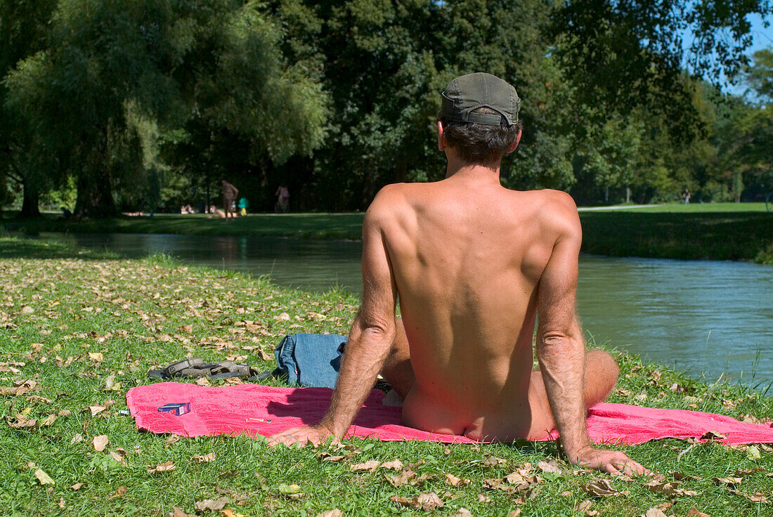 Naked young man sunbathing near Eisbach, English Garden, Schwabing, Munich, Bavaria, Germany