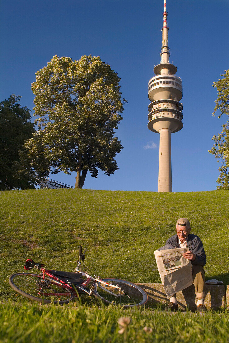 Reading Newspaper in front of Olympic Tower, Munich, Bavaria, Germany, summer