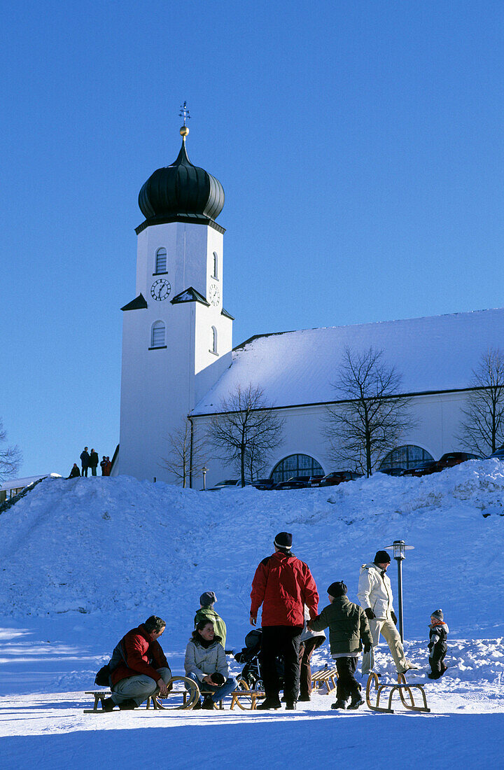 People with sleds, church in background, Sulzberg, Vorarlberg, Austria