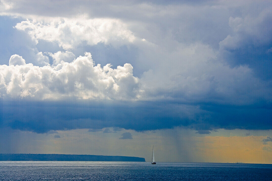 Segelschiff auf dem Meer unter Regenwolken, Mallorca, Balearen, Spanien, Europa