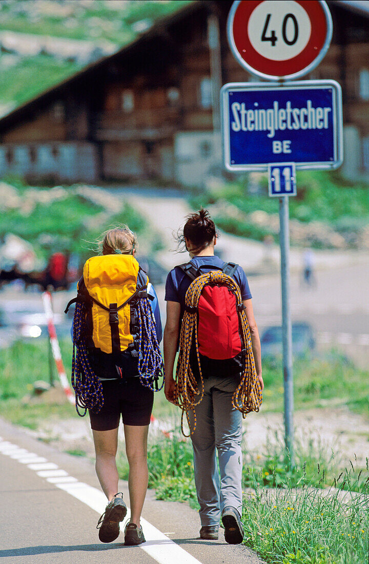 Two young women with climbing equipment walking along street, Bernese Oberland, Canton Bern, Switzerland, MR