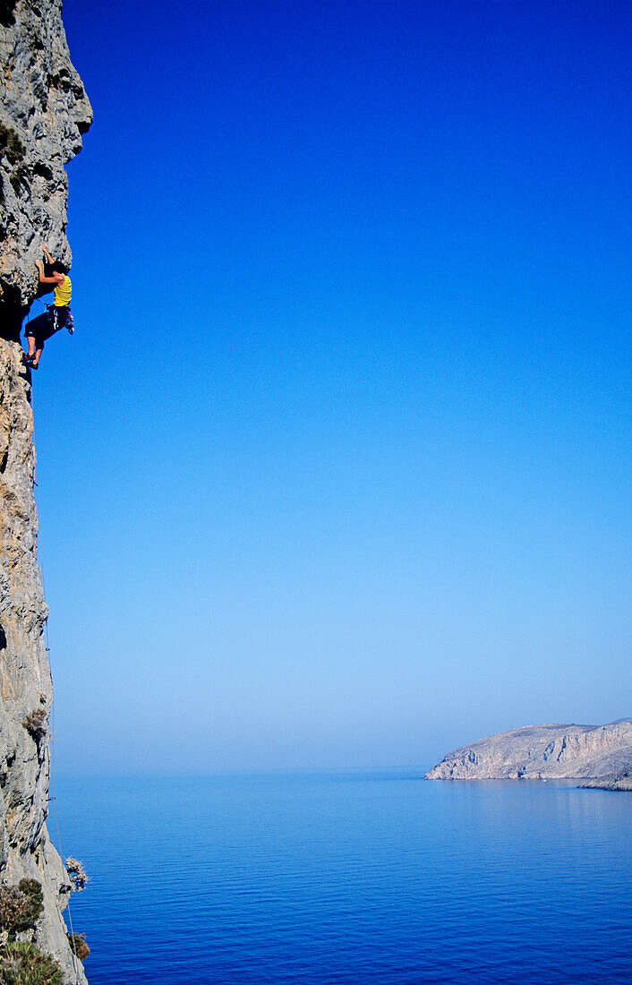 Kalymnos, Greece a woman climbs on a vertical rock pillar above the Aegean Sea, Europe, MR