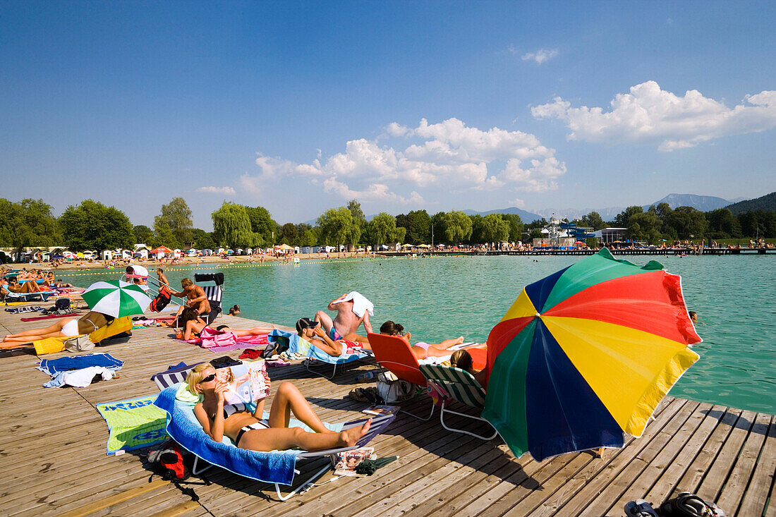 Young people sunbathing on landing stage at Strandbad Klagenfurt, Lake Wörthersee (biggest lake of Carinthia), Klagenfurt, Carinthia, Austria