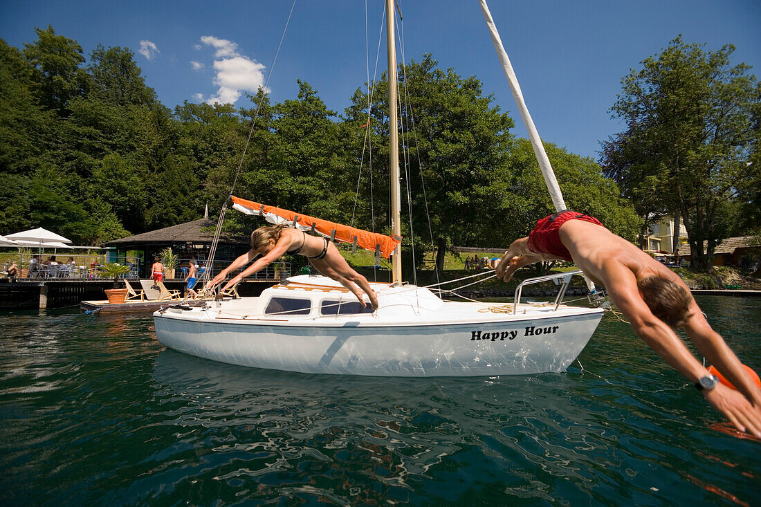 Paar springt vom Segelboot ins Wasser, Millstätter See, tiefster See Kärntens, Millstatt, Kärnten, Österreich