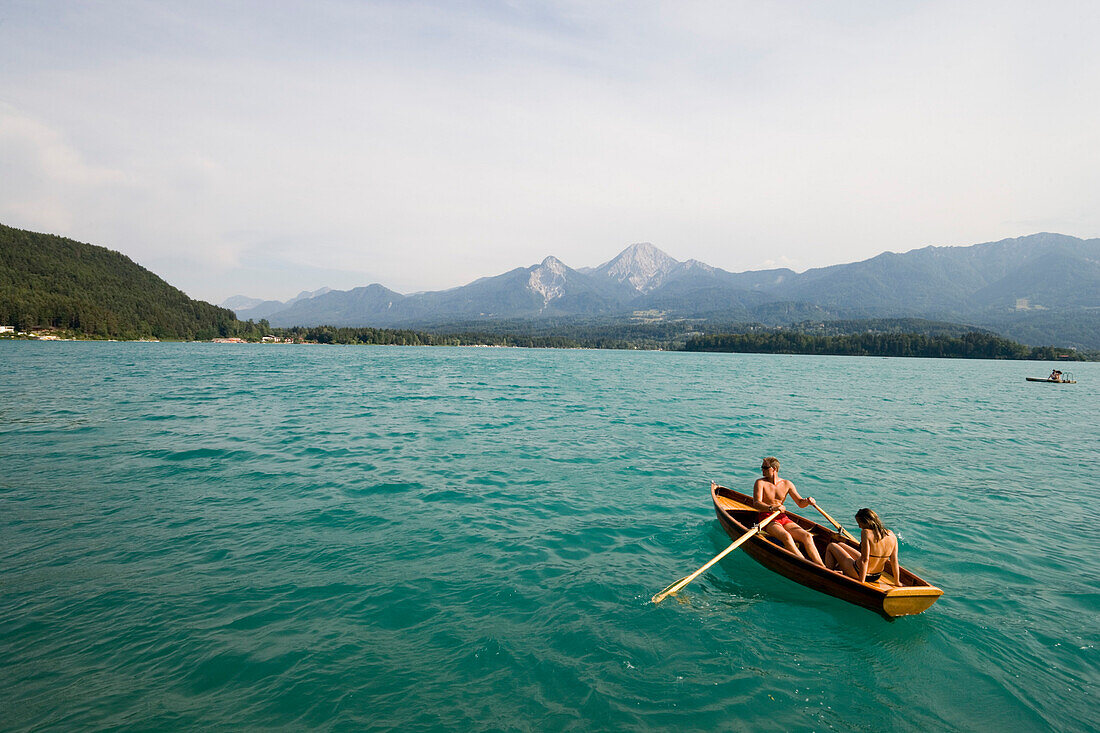 Junges Paar in einem Ruderboot neben ein Bootshaus, Faaker See, Kärnten, Österreich