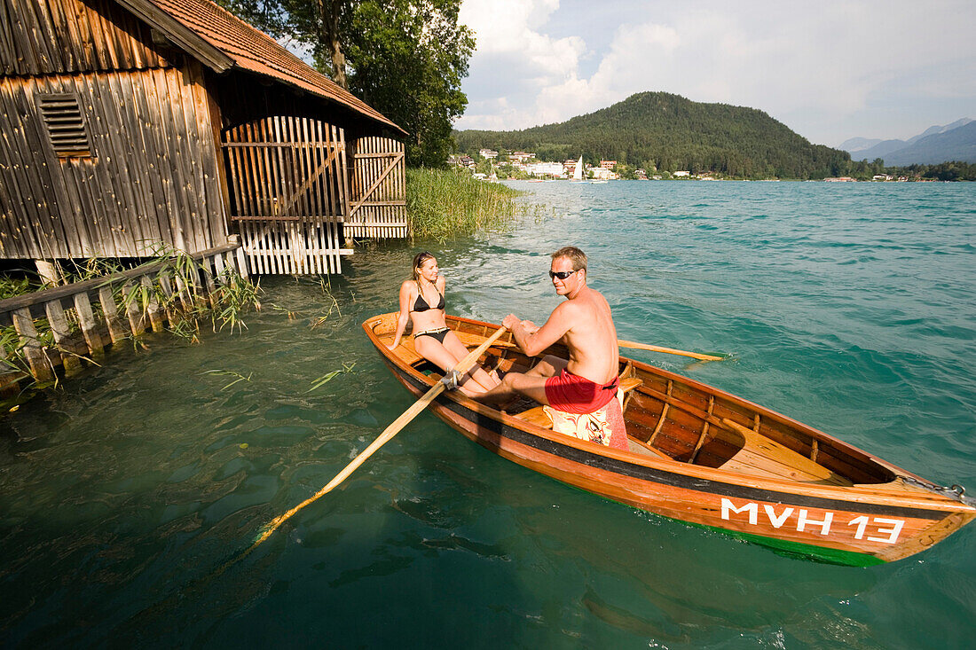 Young couple in a rowing boat on Lake Faak near a boathouse, Carinthia, Austria