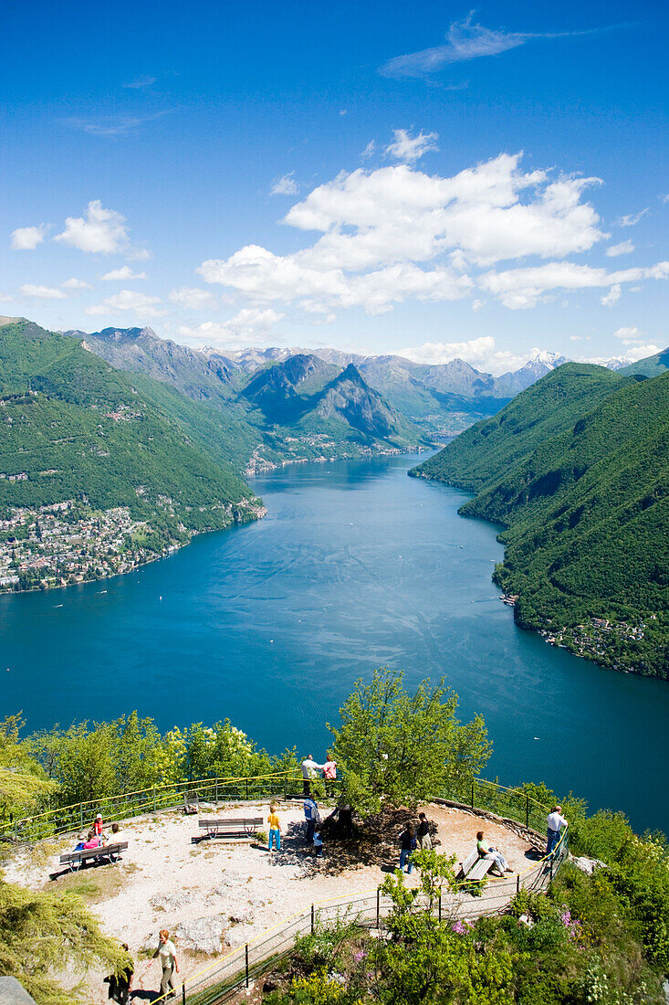 Panoramic view from Monte San Salvatore (912 m) over Lake Lugano and Lugano, people resting on benches, Lugano, Ticino, Switzerland