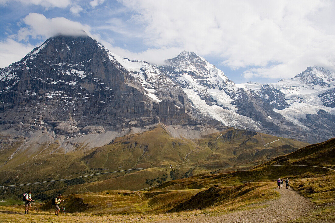 People hiking along Maennlichen panorama hiking path, Eiger 3970 m, Moench 4107 m and Jungfrau 4158 m in the background, Grindelwald, Bernese Oberland, Canton of Bern, Switzerland