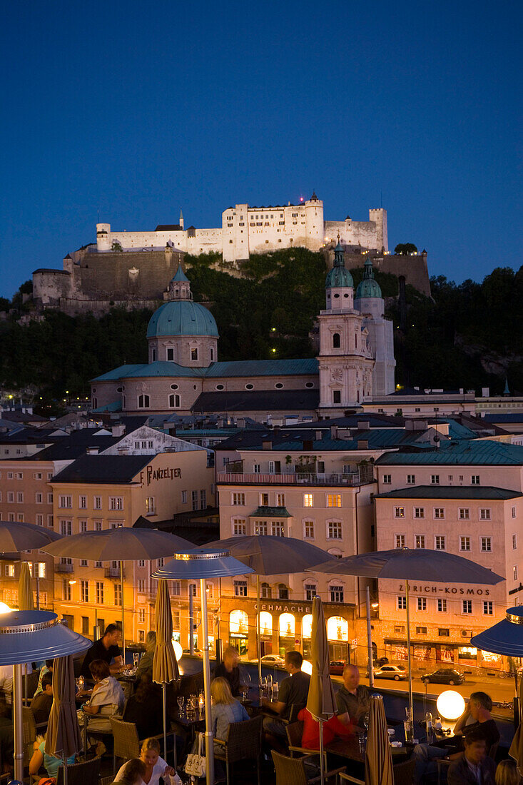 View over illuminated roof deck of restaurant Hotel Stein to old town with Salzburg Cathedral and  Hohensalzburg Fortress, largest, fully-preserved fortress in central Europe, in the evening, Salzburg, Salzburg, Austria, Since 1996 historic centre of the 