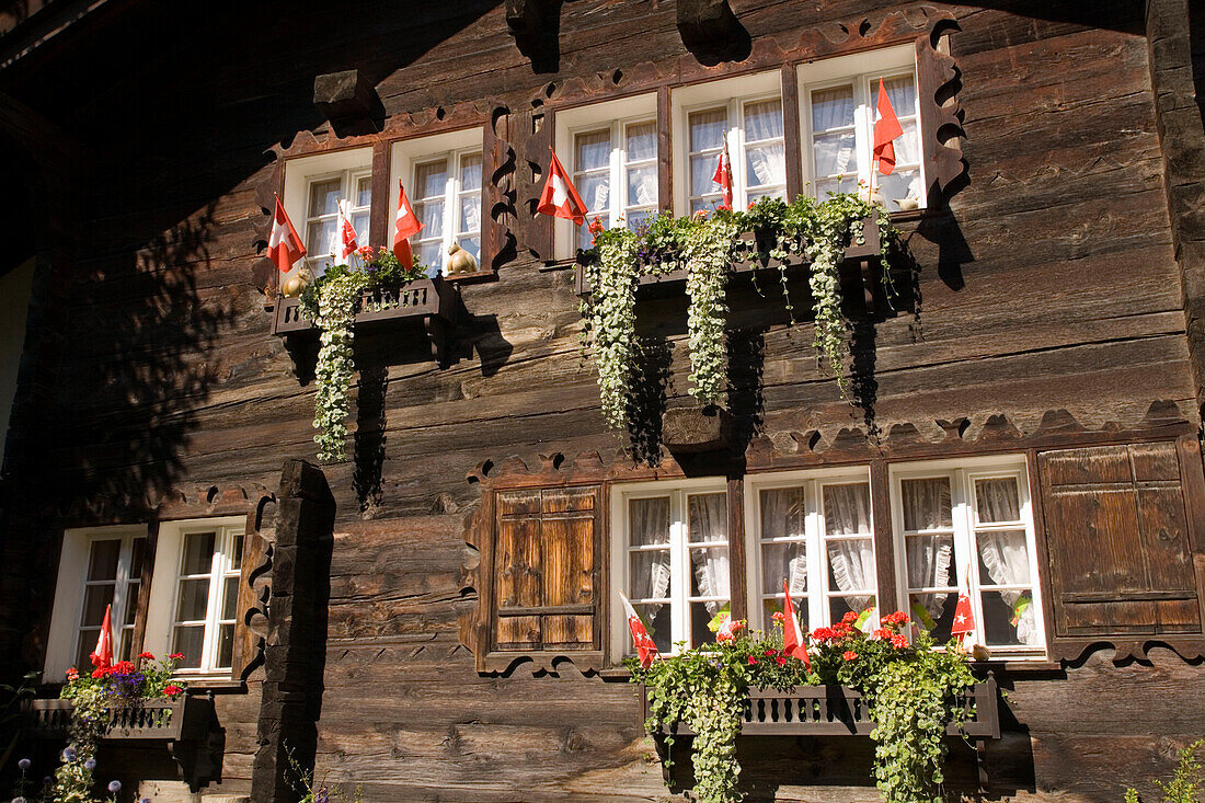 With flower boxes and Swiss flags decorated wooden house, Zermatt village, Zermatt, Valais, Switzerland