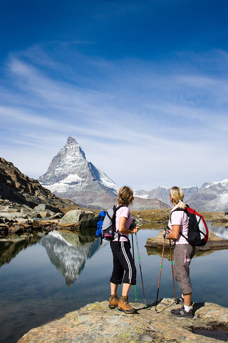 Zwei Frauen betrachten der Spiegelung des Ostwands, Hoernligrat, des Matterhorns, 4478 m, in Riffelsee, Zermatt, Wallis, Schweiz