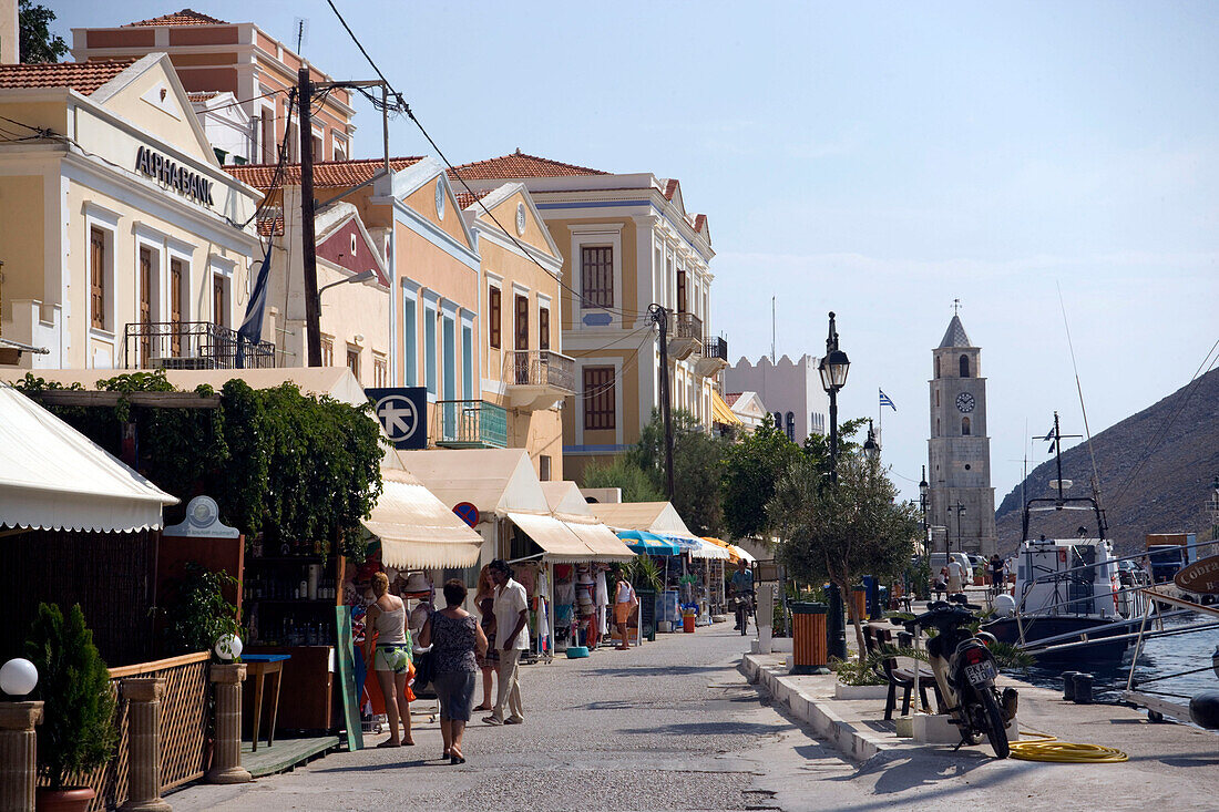 View along promenade to clocktower, Gialos harbour, Simi, Symi Island, Greece