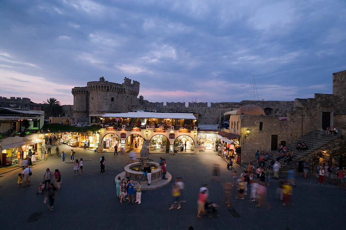 View over busy Platia Ippokratou with Thalassini Gate in background in the evening, Rhodes Town, Rhodes, Greece, (Since 1988 part of the UNESCO World Heritage Site)