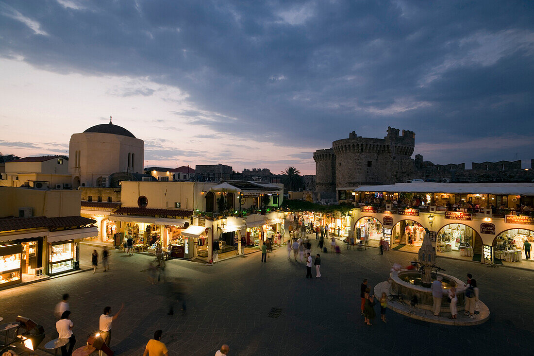 View over busy Platia Ippokratou with Thalassini Gate in background in the evening, Rhodes Town, Rhodes, Greece, (Since 1988 part of the UNESCO World Heritage Site)