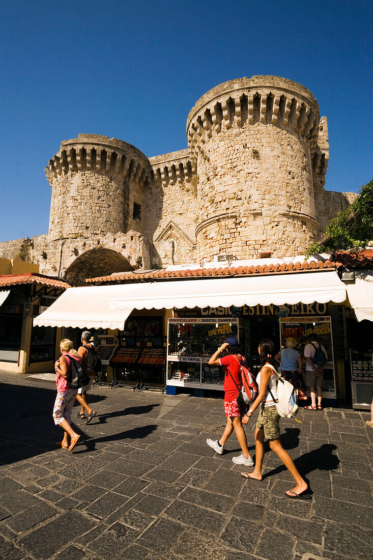 People strolling over Platia Ippokratou with shops, Thalassini Gate in background, Rhodes Town, Rhodes, Greece, (Since 1988 part of the UNESCO World Heritage Site)
