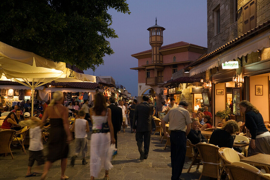 People strolling along shopping street Odos Sokratous, passing a pavement cafe, Rhodes Town, Rhodes, Greece, (Since 1988 part of the UNESCO World Heritage Site)
