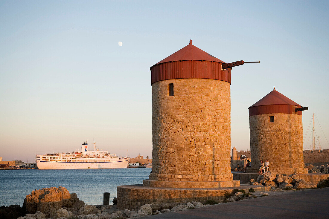 Traditional windmills on mole at Mandraki harbour (translated literally: fold), cruiser in background, Rhodes Town, Rhodes, Greece