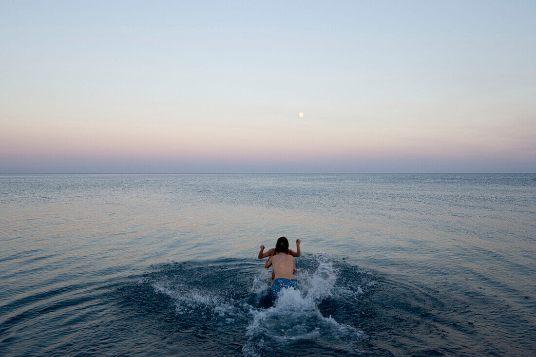 Young couple in water, man jumping in Gennadi beach, Gennadi, Rhodes, Greece