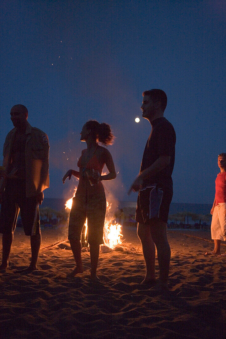 Young people standing on beach near a campfire, sunday party at Sundance Beach Bar, Gennadi beach, Gennadi, Rhodes, Greece