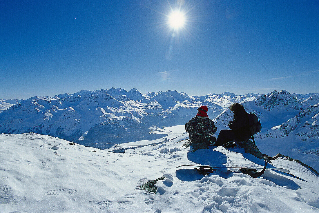Two people sitting in the snow, Corviglia, St. Moritz, Engadin, Grisons, Switzerland, Europe