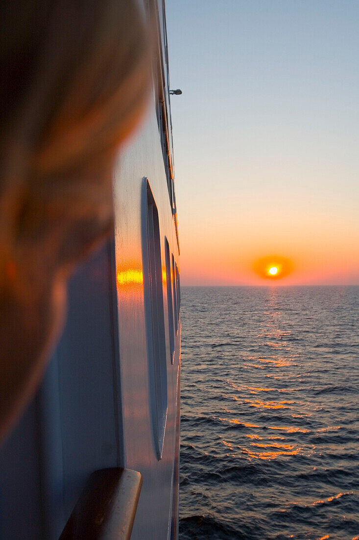 Frau blickt in den Sonnenuntergang von an Bord der MS Europa während Ostsee-Kreuzfahrt, Europa