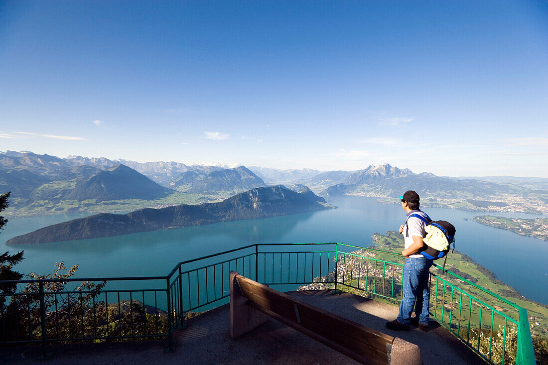 Man standing on vantage point Känzli, mount Rigi (1797 m, Queen of the Mountains) and looking over Lake Lucerne with Weggis, mount Bürgenstock and mount Pilatus (2132 M), Rigi Kaltbad, Canton of Schwyz, Switzerland