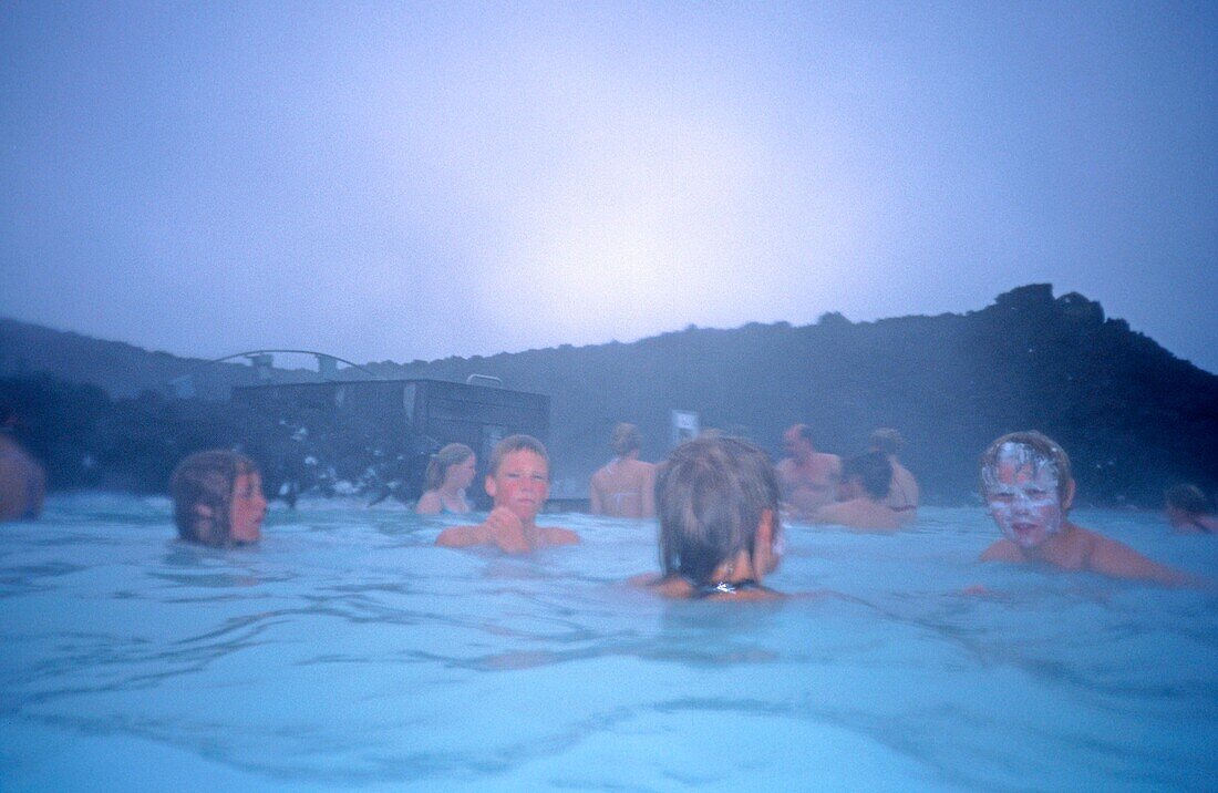 Iceland, Blue Lagoon near Rejkjavik, boys with white facial mask in thermal pool, fog