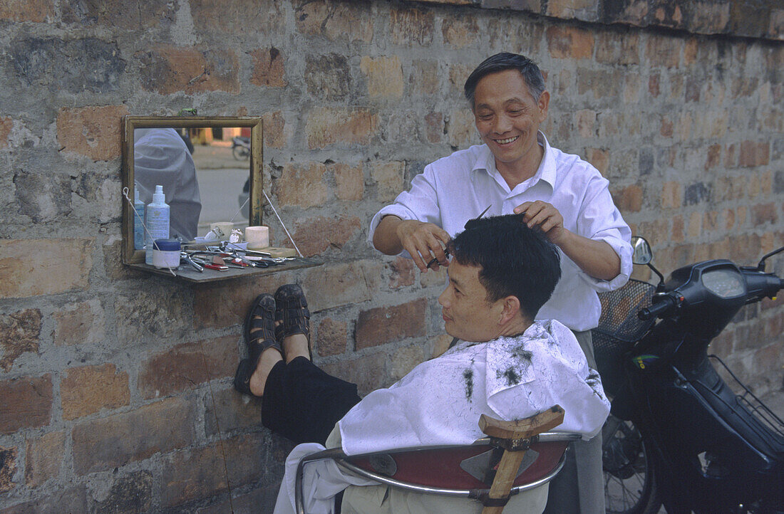 Hanoi, Friseur mit Kunde beim open air Haareschneiden