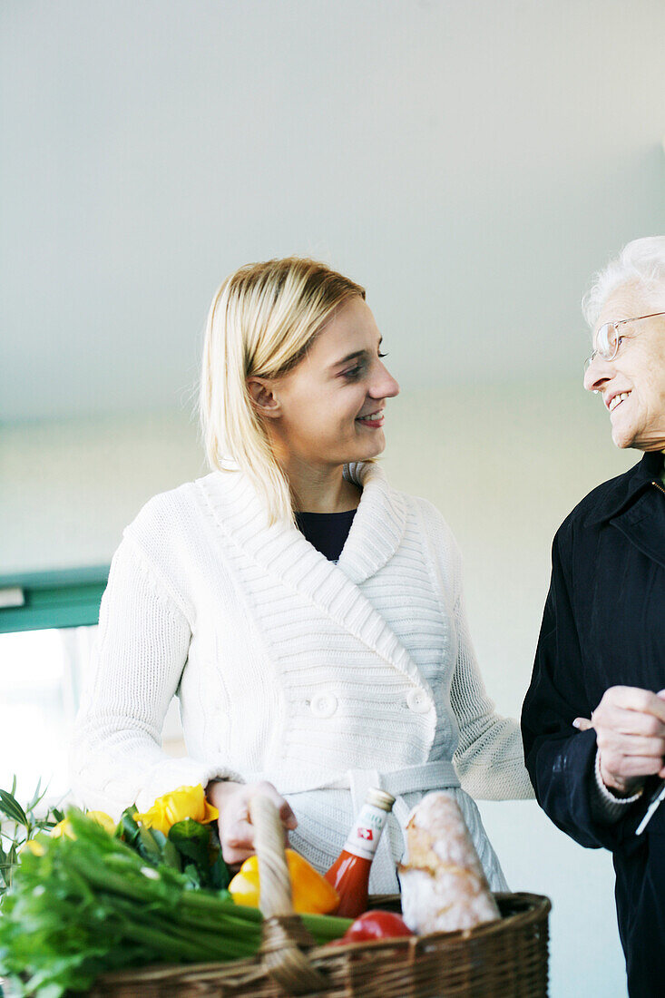 Young woman helps an elderly lady and carries the shopping