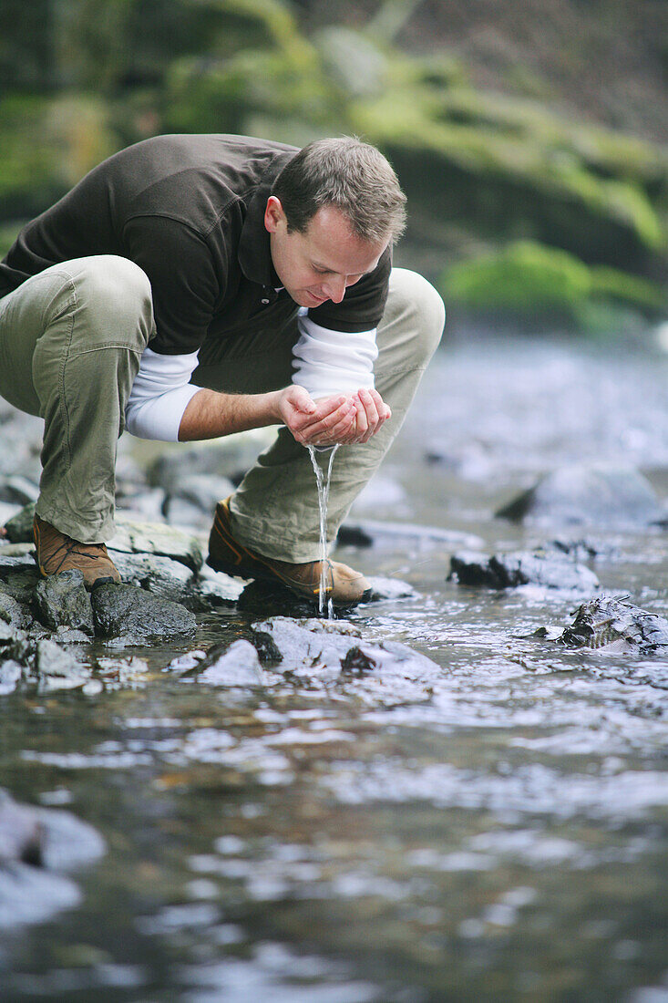 Mann trinkt Wasser am Fluß, Wellness, Gesundheit, Natur