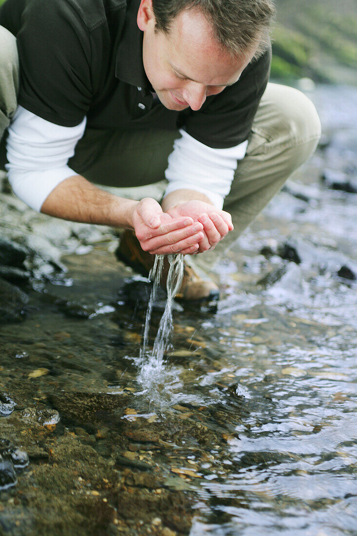 Man drinking water from a stream