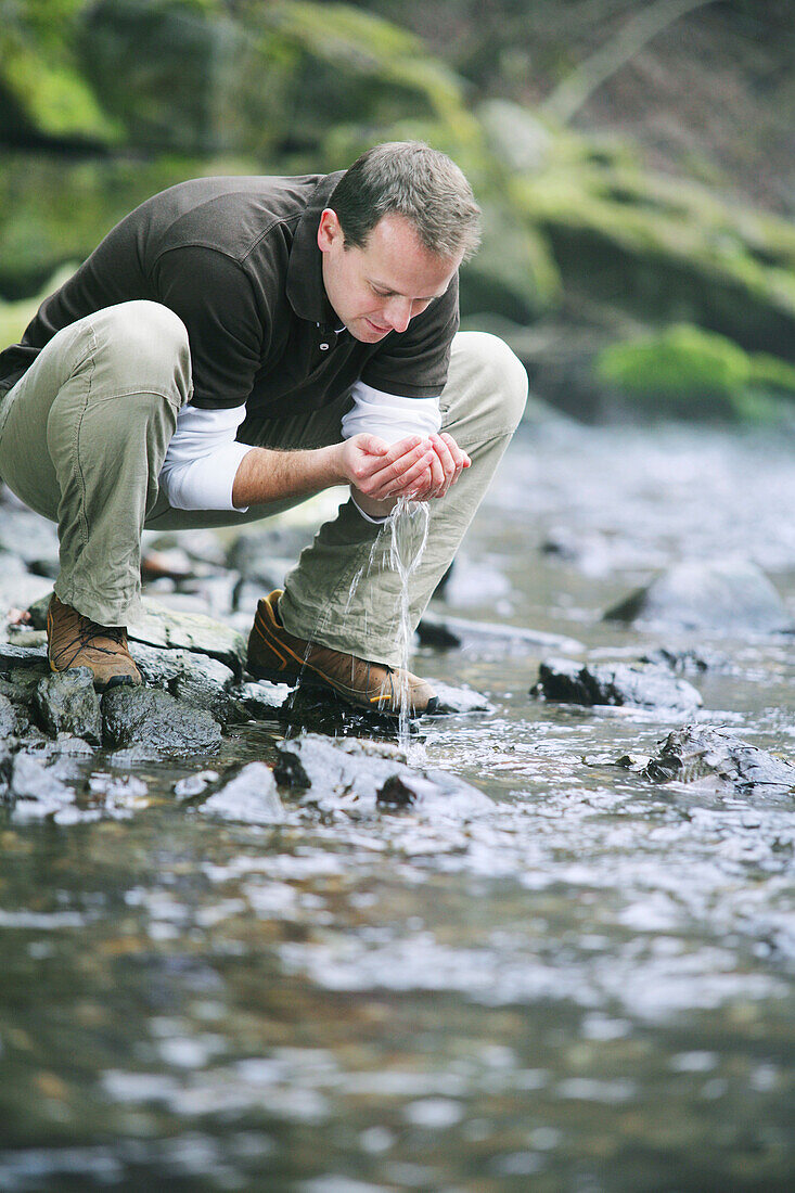 Man drinking water from a stream