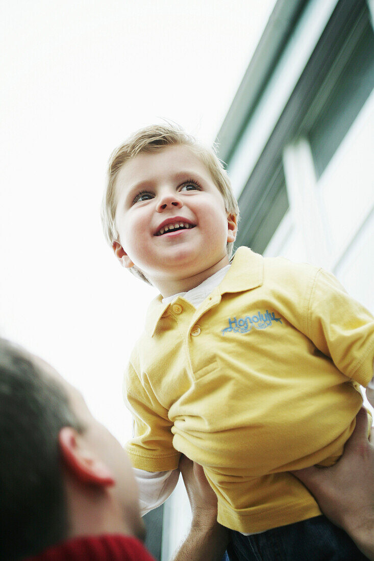 Father lifts son in the air, laughing