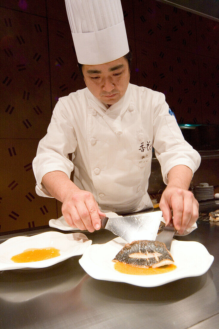 Cook putting fish on a plate, Tokyo, Japan, Asia