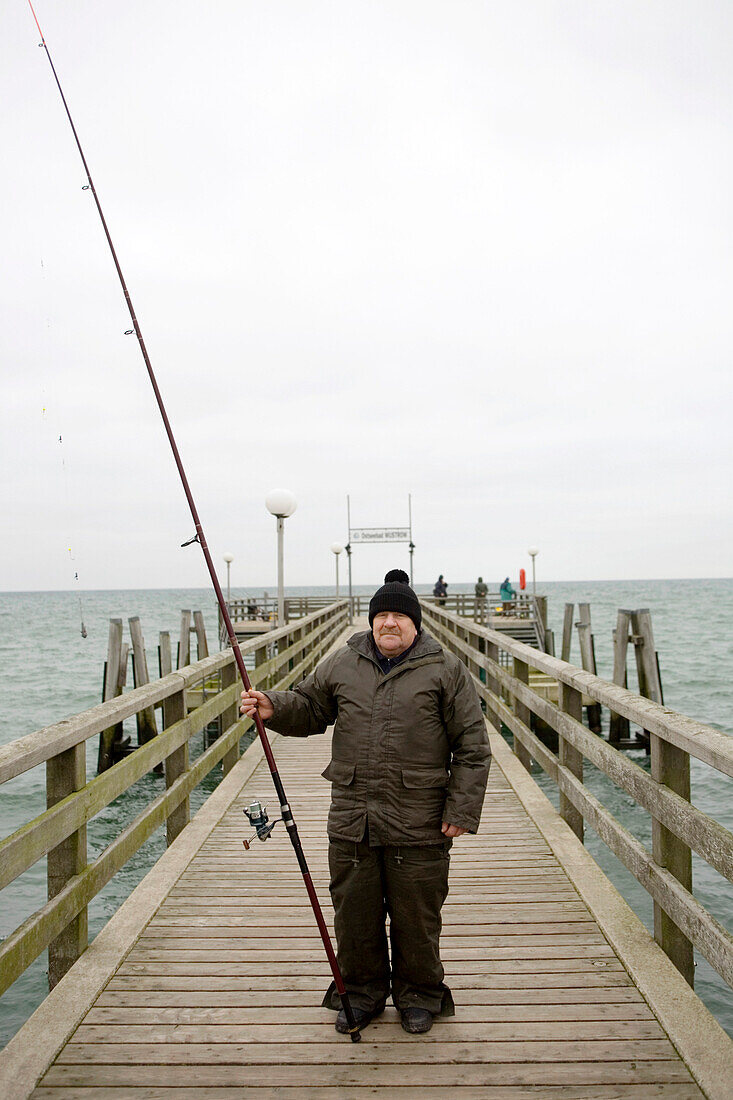 Seniro man with fishing rod on pear at Baltic Sea, Mecklenburg-Western Pomerania, Germany