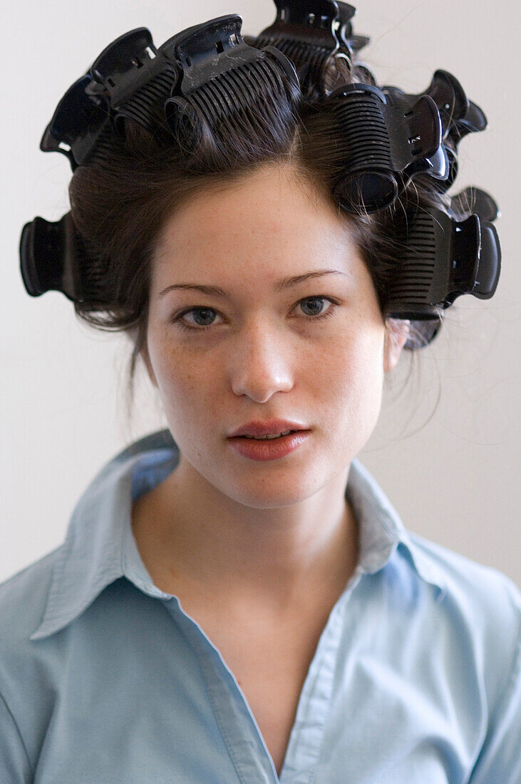 Young woman with curlers in hair, portrait