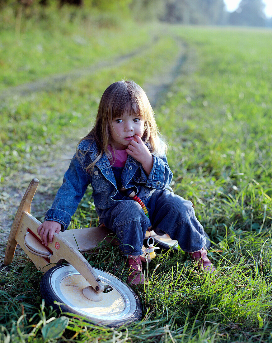 A girl with wooden walker bike, on the riverbanks of the Inn, near Bad Füssing, Bavaria, Germany