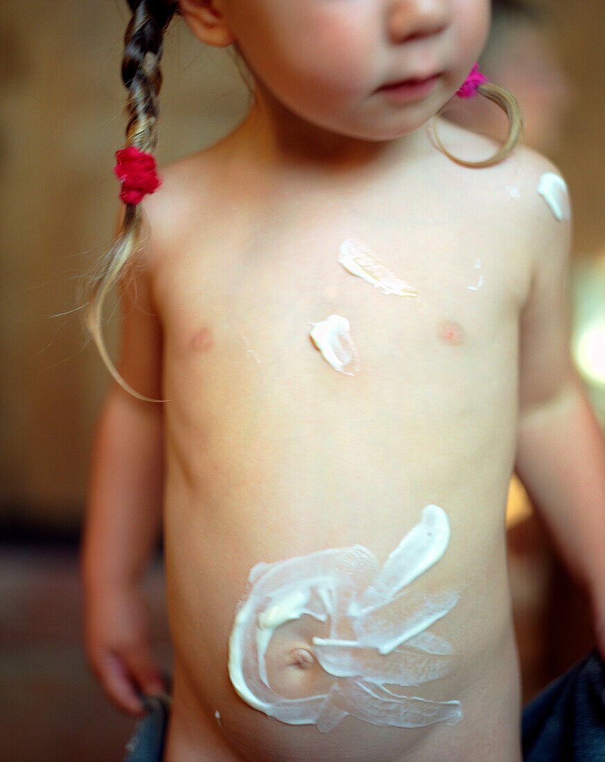 Girl painted with face pack on belly, Germany