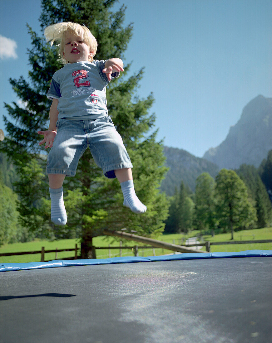 Junge hüpft auf Trampolin, Simmental, Berner Alpen, Kanton Bern, Schweiz