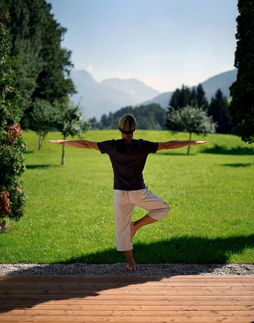 Mann macht Yoga im Garten, Leogang, Salzburg, Österreich