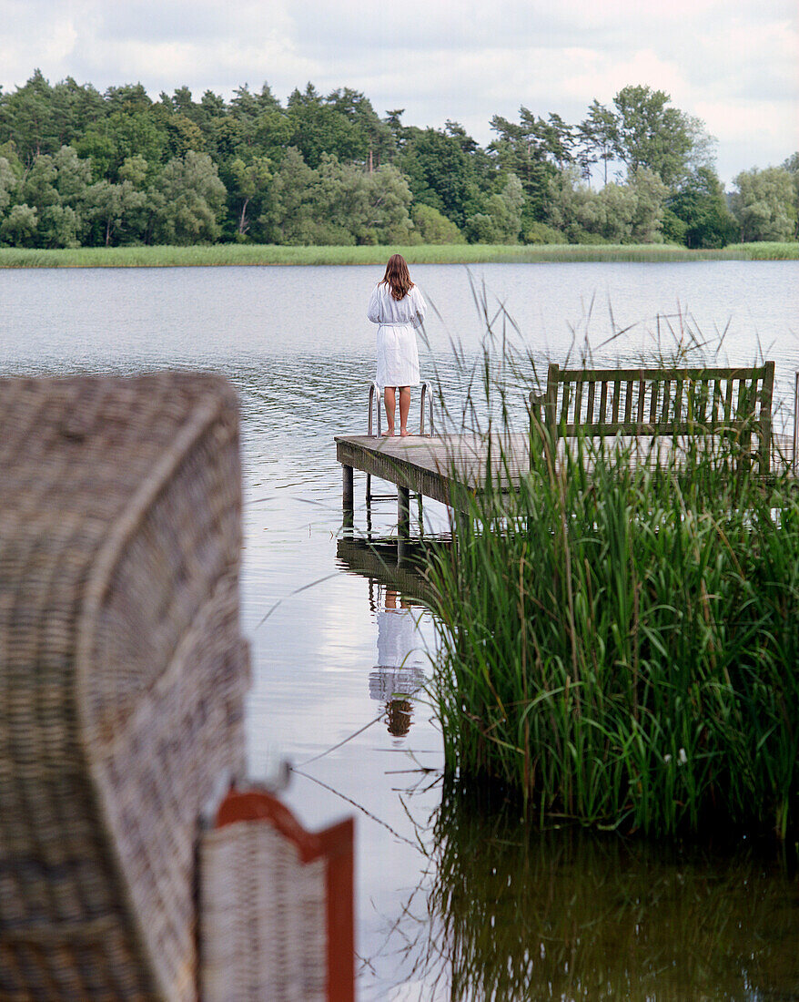 Frau steht auf einem Steg am See, Seehotel Neuklostersee, Nakenstorf, Mecklenburg-Vorpommern, Deutschland