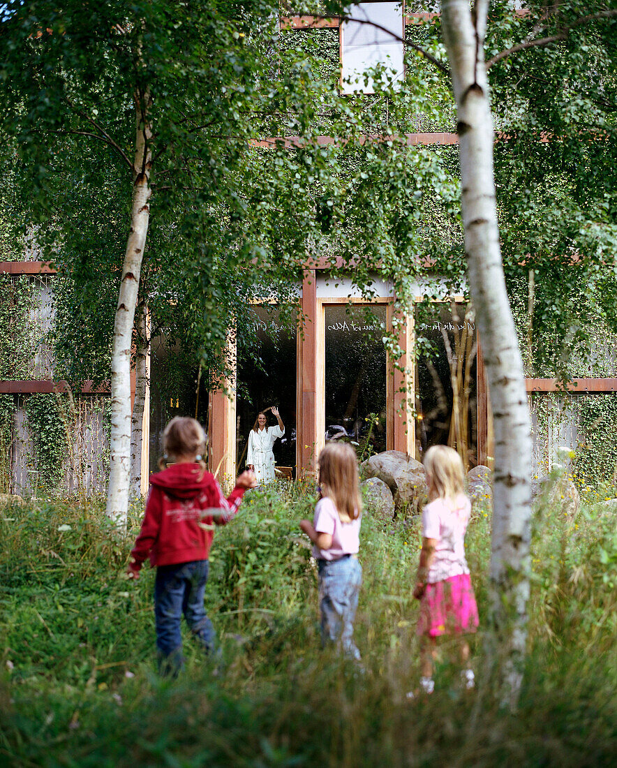Children in the garden waving to mother at the window of a Wellness Hotel, guests in the garden of Spa Hotel Seehotel Neuklostersee, Mecklenburg - Western Pomerania, Germany