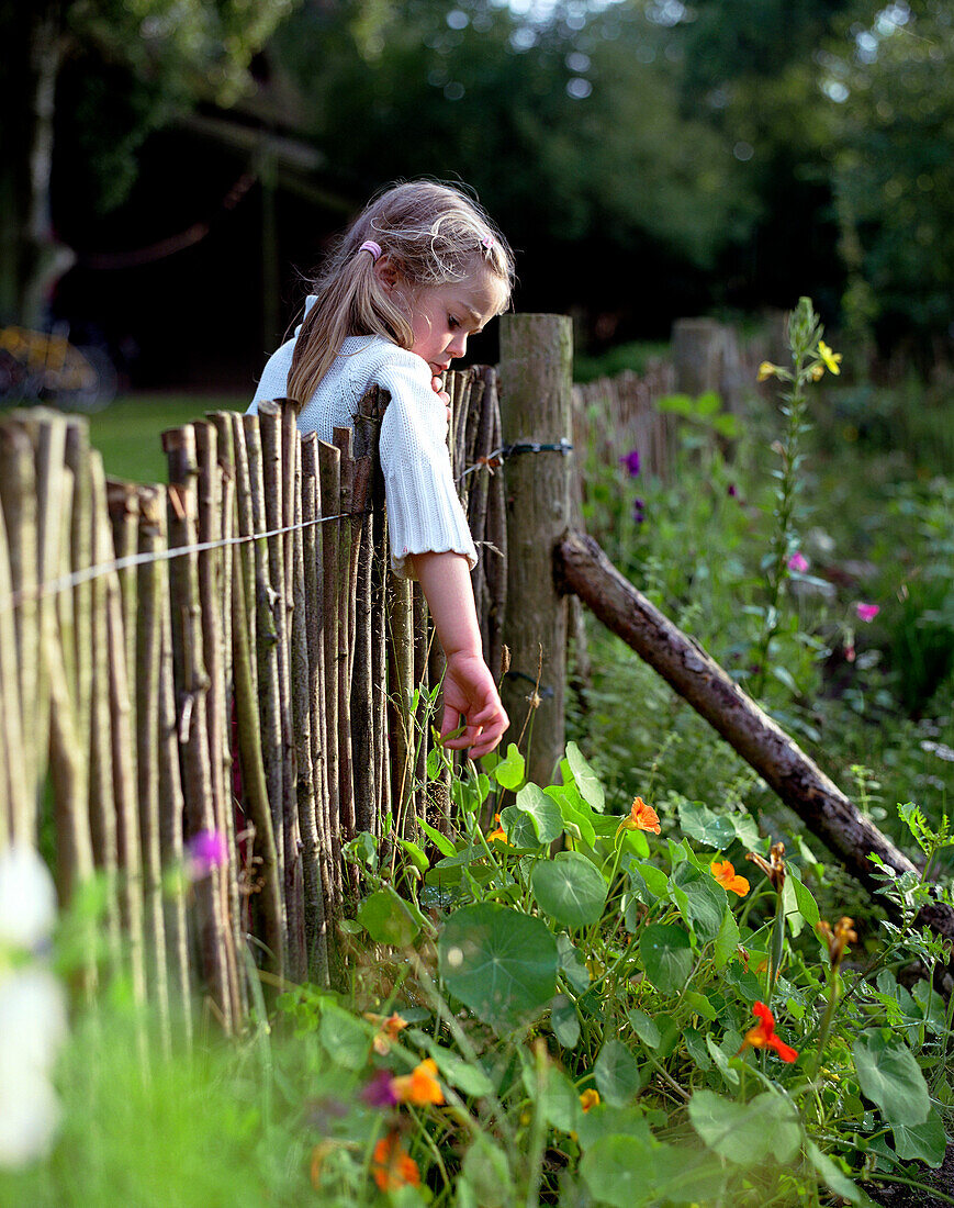 Girl looking over the fence in the kitchen garden, spa area of Seehotel Neuklostersee, Mecklenburg - Western Pomerania, Germany