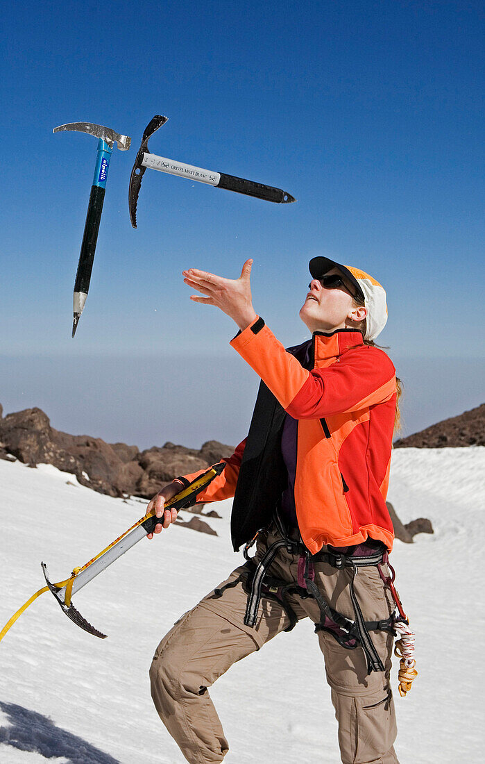 Mid adult woman juggling with ice axes, High Atlas Mountains, Morocco