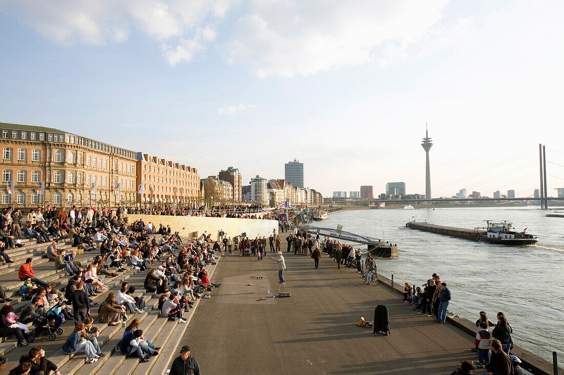 Leute sitzen an der Rheinpromenade am Rheinufer, Altstadt, Düsseldorf, Nordrhein-Westfalen, Deutschland
